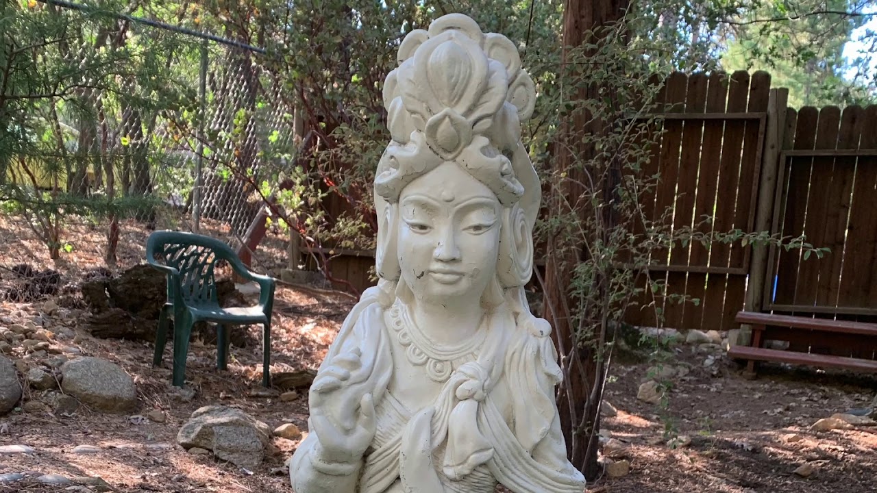 A statue of a woman in the woods.